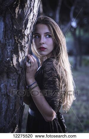 Stock Image - Young woman hiding in a forest; Tarifa, Cadiz, Andalusia, Spain. Fotosearch