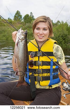 Stock Image - Young woman holding a large brook trout; Ontario, Canada. Fotosearch