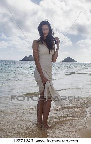 Young woman in white dress on the beach at the water's edge; Kailua, Island of Hawaii, Hawaii, United States of America View Large Photo Image Stock Photo - Young woman in white dress on the beach at the water's edge; Kailua, Island of Hawaii, Hawaii, United States of America. Fotosearch