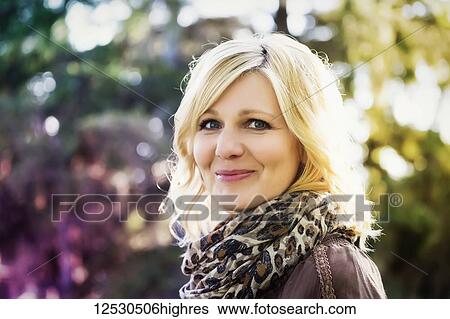 Stock Photograph - A beautiful blonde middle-aged woman poses for the camera while spending time in a park on a warm summer evening; St. Alberta, Alberta, Canada. Fotosearch