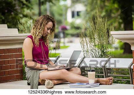 A beautiful young female university student sits working on her laptop on a park bench outside in the campus; Edmonton, Alberta, Canada View Large Photo Image Stock Photograph - A beautiful young female university student sits working on her laptop on a park bench outside in the campus; Edmonton, Alberta, Canada. Fotosearch