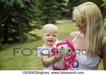 Stock Photograph - A beautiful young mom walking with her baby daughter while enjoying quality time together outdoors in a park on a warm summer day; Edmonton, Alberta, Canada. Fotosearch