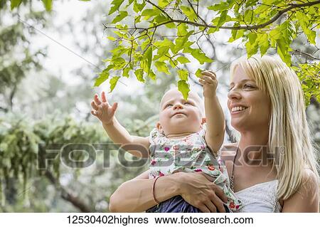 A beautiful young mother with long blonde hair enjoying quality time with her cute baby daughter in a city park on a summer day; Edmonton, Alberta, Canada View Large Photo Image Stock Photograph - A beautiful young mother with long blonde hair enjoying quality time with her cute baby daughter in a city park on a summer day; Edmonton, Alberta, Canada. Fotosearch