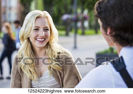 Stock Photograph - A beautiful young woman talking to her boyfriend in the university campus; Edmonton, Alberta, Canada. Fotosearch