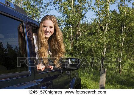 A beautiful young woman with long blond hair looking out a vehicle window and posing for the camera; Edmonton, Alberta, Canada View Large Photo Image Stock Photograph - A beautiful young woman with long blond hair looking out a vehicle window and posing for the camera; Edmonton, Alberta, Canada. Fotosearch