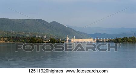 Stock Photograph - A bridge and dam on the Danube River with hills in the distance, the largest dam on the Danube river and one of the largest hydro power plants in Europe. Iron Gate Hydroelectric Power Station; Drobeta-Turnu Severin, Jude? ul Mehedin? i, Serbia. Fotosearch