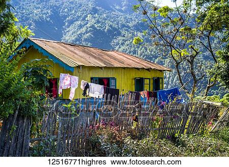 Stock Photograph - A bright yellow house with blue trim and a clothesline hanging outside in the Himalayas; West Bengal, India. Fotosearch