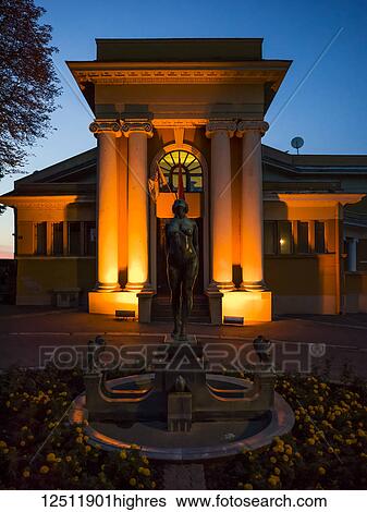 A building illuminated with golden light at dusk with a clear sky and a water fountain in a garden; Belgrade, Vojvodina, Serbia View Large Photo Image Stock Photograph - A building illuminated with golden light at dusk with a clear sky and a water fountain in a garden; Belgrade, Vojvodina, Serbia. Fotosearch