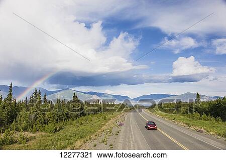 A car drives on the Alaska Highway adjacent to Kluane Lake with atmospheric rain clouds and a Rainbow in the background, Yukon Territory, Canada, Summer View Large Photo Image Stock Image - A car drives on the Alaska Highway adjacent to Kluane Lake with atmospheric rain clouds and a Rainbow in the background, Yukon Territory, Canada, Summer. Fotosearch