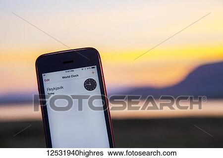 A cell phone displays the local time close to midnight in Reykjavik close to midnight with the daylight still visible at summer solstice, when the sun doesn't fully set in Iceland even at midnight; Reykjavik, Iceland View Large Photo Image Stock Photograph - A cell phone displays the local time close to midnight in Reykjavik close to midnight with the daylight still visible at summer solstice, when the sun doesn't fully set in Iceland even at midnight; Reykjavik, Iceland. Fotosearch