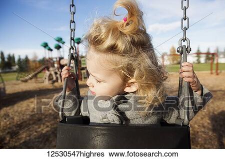 A cute young girl looking away while swinging in a playground during the fall season; Spruce Grove, Alberta, Canada View Large Photo Image Stock Photograph - A cute young girl looking away while swinging in a playground during the fall season; Spruce Grove, Alberta, Canada. Fotosearch
