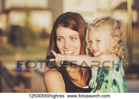 A cute young girl with her mother after playing in a playground during the fall season; Spruce Grove, Alberta, Canada View Large Photo Image Stock Photograph - A cute young girl with her mother after playing in a playground during the fall season; Spruce Grove, Alberta, Canada. Fotosearch