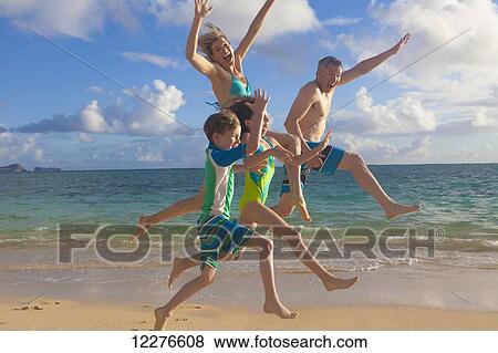 Stock Photo - A family of four on the beach on a hawaiian island; Kailua, Island of Hawaii, Hawaii, United States of America. Fotosearch
