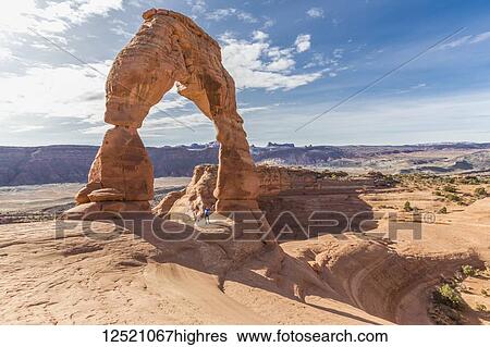 A female hiker stands celebrating under the Delicate Arch in Arches National Park; Moab, Utah, United States of America View Large Photo Image Stock Photograph - A female hiker stands celebrating under the Delicate Arch in Arches National Park; Moab, Utah, United States of America. Fotosearch