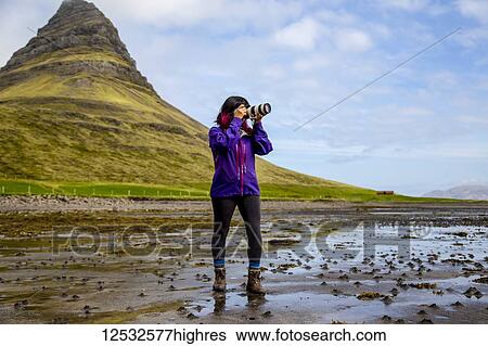 A female hiker stops on the beach at low tide to take a photo with an SLR camera in front of Kirkjufell Mountain in Snaefellsnes peninsula, Western Iceland; Iceland View Large Photo Image Stock Photograph - A female hiker stops on the beach at low tide to take a photo with an SLR camera in front of Kirkjufell Mountain in Snaefellsnes peninsula, Western Iceland; Iceland. Fotosearch