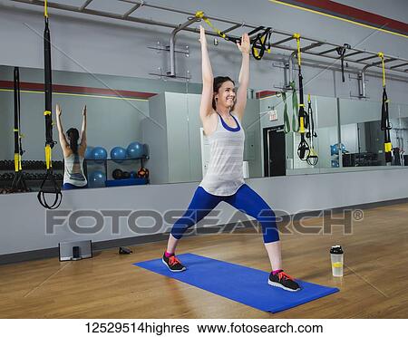 Stock Photograph - A fitness trainer doing a warrior 1 yoga pose at a gym; Spruce Grove, Alberta, Canada. Fotosearch