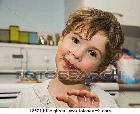 Stock Photograph - A grinning young boy icking fingers and getting messy after making fudge; Langley, British Columbia, Canada. Fotosearch