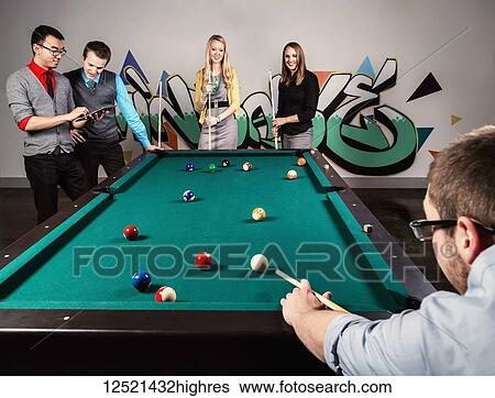 Stock Photograph - A group of young millennial business professionals playing a game of pool together on a work break; Sherwood Park, Alberta, Canada. Fotosearch