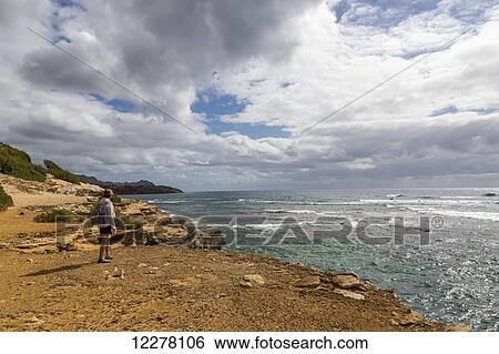 A hiker stands on a cliff watching an approaching rain storm; Poipu, Kauai, Hawaii, United States of America View Large Photo Image Stock Photograph - A hiker stands on a cliff watching an approaching rain storm; Poipu, Kauai, Hawaii, United States of America. Fotosearch