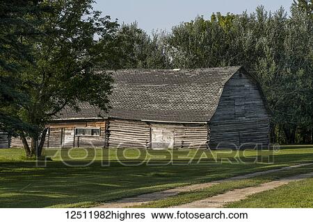 Stock Photograph - A log barn with leaning walls and a weathered roof; Manitoba, Canada. Fotosearch