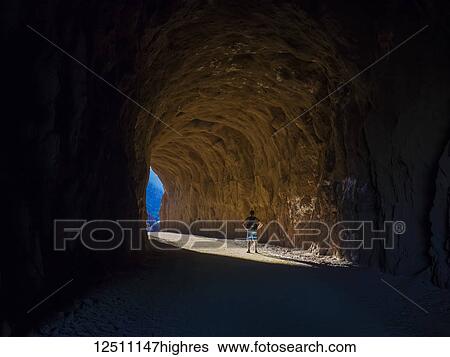 Stock Photograph - A man hikes through a tunnel in the Nevada spring desert; Boulder City, Nevada, United States of America. Fotosearch