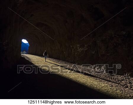 Stock Photograph - A man hikes through a tunnel in the Nevada spring desert; Boulder City, Nevada, United States of America. Fotosearch