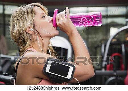 Stock Photograph - A middle-aged woman working out at a gym and drinking from a water bottle; Spruce Grove, Alberta, Canada. Fotosearch