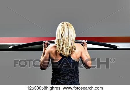 Stock Photograph - A middle-aged woman working out at a fitness facility doing chin-ups; Spruce Grove, Alberta, Canada. Fotosearch