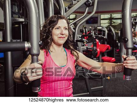 A middle-aged woman working out using a chest fly at a fitness facility; Spruce Grove, Alberta, Canada View Large Photo Image Stock Photograph - A middle-aged woman working out using a chest fly at a fitness facility; Spruce Grove, Alberta, Canada. Fotosearch