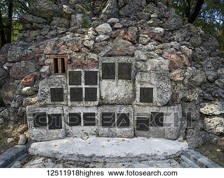 Stock Photograph - A monument with the portraits of men's faces on metal plates and mounted on a stone wall; Belgrade, Vojvodina, Serbia. Fotosearch