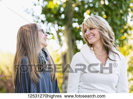 Stock Photograph - A mother and daughter walking and laughing together in a park in autumn; Edmonton, Alberta, Canada. Fotosearch