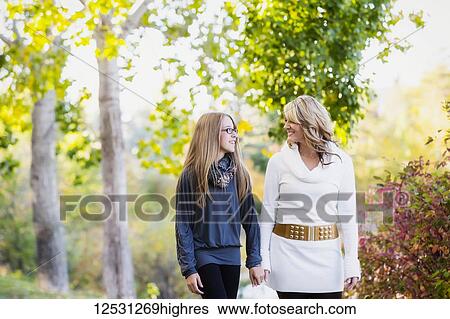 A mother and daughter walking, holding hands and talking together in a park in autumn; Edmonton, Alberta, Canada View Large Photo Image Stock Photograph - A mother and daughter walking, holding hands and talking together in a park in autumn; Edmonton, Alberta, Canada. Fotosearch