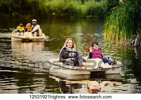 Stock Photograph - A mother and father take their three sons paddle boating on a lake in a city park; Edmonton, Alberta, Canada. Fotosearch