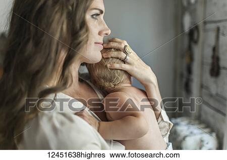 A mother holds her young baby girl and cradles her head with her hand while snuggling after nap time; Sorrento, British Columbia, Canada View Large Photo Image Stock Photograph - A mother holds her young baby girl and cradles her head with her hand while snuggling after nap time; Sorrento, British Columbia, Canada. Fotosearch