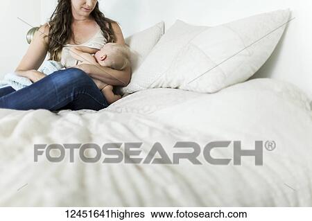 A mother holds her young baby girl and breastfeeds her on her bed; Sorrento, British Columbia, Canada View Large Photo Image Stock Photograph - A mother holds her young baby girl and breastfeeds her on her bed; Sorrento, British Columbia, Canada. Fotosearch
