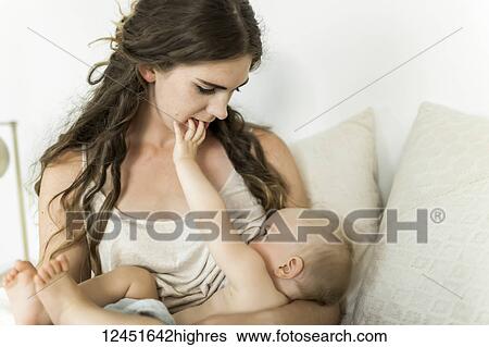 A mother holds her young baby girl and breastfeeds her on her bed; Sorrento, British Columbia, Canada View Large Photo Image Stock Photograph - A mother holds her young baby girl and breastfeeds her on her bed; Sorrento, British Columbia, Canada. Fotosearch