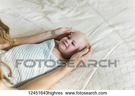 A mother's arms and hands cradle a swadled baby girl as she looks up to her mother; Sorrento, British Columbia, Canada View Large Photo Image Stock Photograph - A mother's arms and hands cradle a swadled baby girl as she looks up to her mother; Sorrento, British Columbia, Canada. Fotosearch