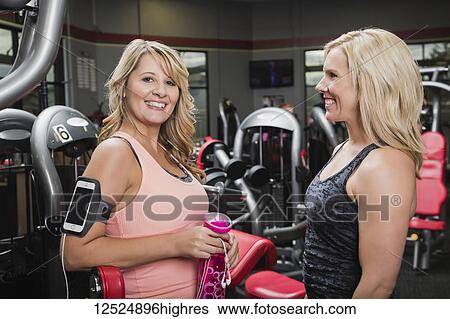 Stock Photograph - A personal trainer and her client pausing and talking after working out at a fitness facility; Spruce Grove, Alberta, Canada. Fotosearch