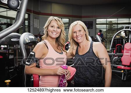 Stock Photograph - A personal trainer and her client pausing and posing for the camera after working out at a fitness facility; Spruce Grove, Alberta, Canada. Fotosearch