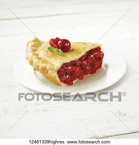 Stock Photograph - A piece of cherry pie on a white plate with fresh cherries garnishing the top. Fotosearch