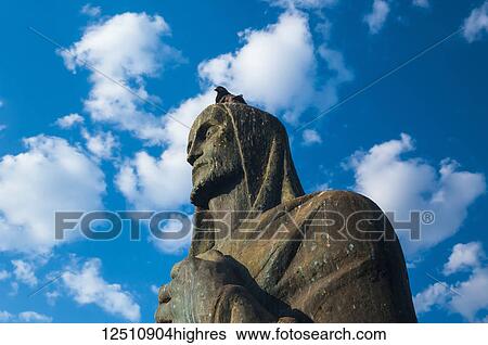 Stock Photograph - A pigeon sits on the head of an evangelist bronze sculpture outside the Cathedral of Brasilia; Brasilia, Brazil. Fotosearch