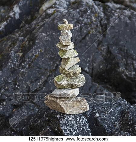 Stock Photograph - A pile of rocks balancing on a black boulder on Tonquin Beach, Vancouver Island; British Columbia, Canada. Fotosearch