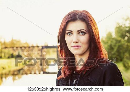 A portrait of a beautiful young woman with red hair standing on the shore of river with a historic, iconic, trestle bridge in the background; St. Albert, Alberta, Canada View Large Photo Image Stock Photograph - A portrait of a beautiful young woman with red hair standing on the shore of river with a historic, iconic, trestle bridge in the background; St. Albert, Alberta, Canada. Fotosearch