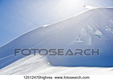 Stock Photograph - A professional, freeriding snowboarder in mid-air on a snowy slope against a blue sky; British Columbia, Canada. Fotosearch