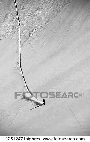 Stock Photograph - A professional, freeriding snowboarder on a wide open snowy slope making new tracks; British Columbia, Canada. Fotosearch