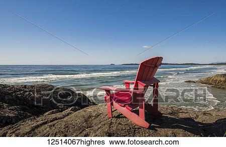 Stock Photograph - A red muskoka chair on the shore along the coast, Pacific Rim National park, Vancouver Island; British Columbia, Canada. Fotosearch