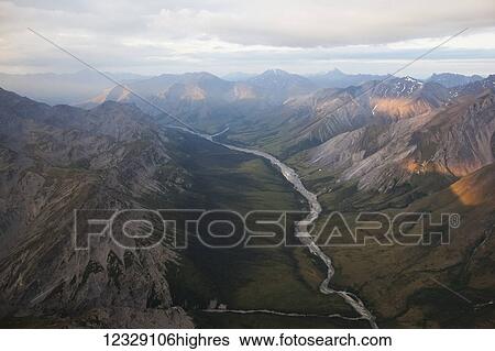 Stock Photograph - A river running through a valley in a rugged mountain range; Alaska, United States of America. Fotosearch