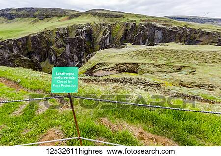 Stock Photograph - A sign reads keep out Flora Protected Area written in English and Icelandic and posted along a fence at a tourism location of Fjadrargljufur; Iceland. Fotosearch