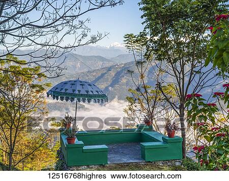 Stock Photograph - A small green terrace with umbrella decorated with plants and overlooking the mountains and valley; West Bengal, India. Fotosearch