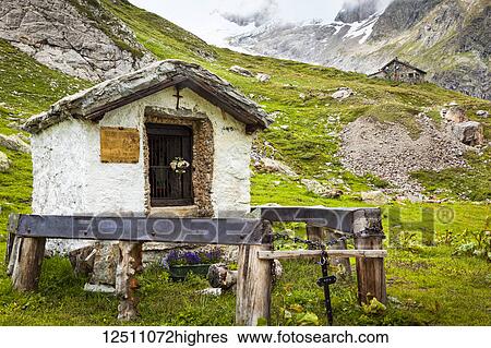 Stock Photograph - A small, historic shrine at Val Veni with Rifugio Elisabetta in the background, Alps; Aosta Valley, Italy. Fotosearch